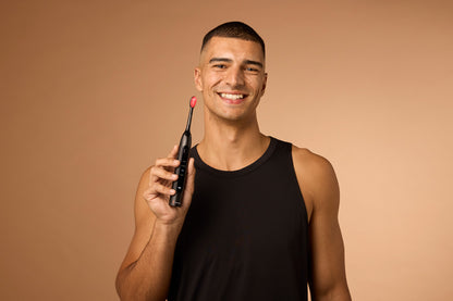 Man holding a black and red toothbrush against a beige background