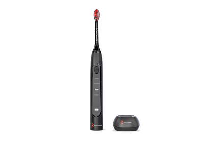 Black electric toothbrush with red bristles next to toothbrush holder